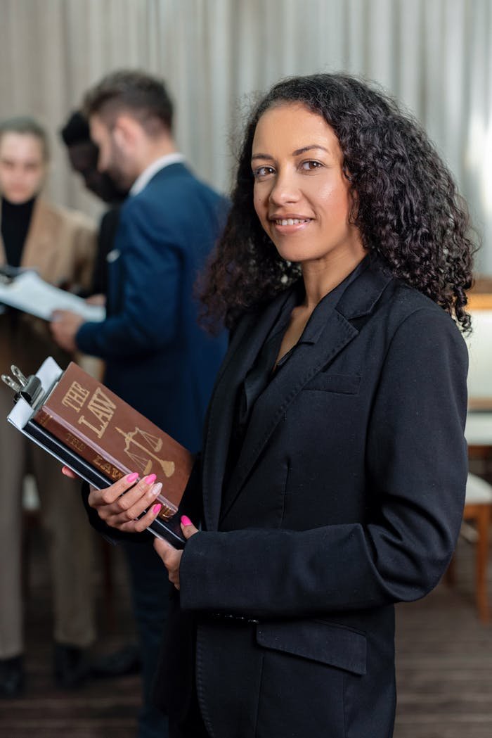 African American female lawyer holding a law book in an office setting, showcasing professionalism and legal expertise.